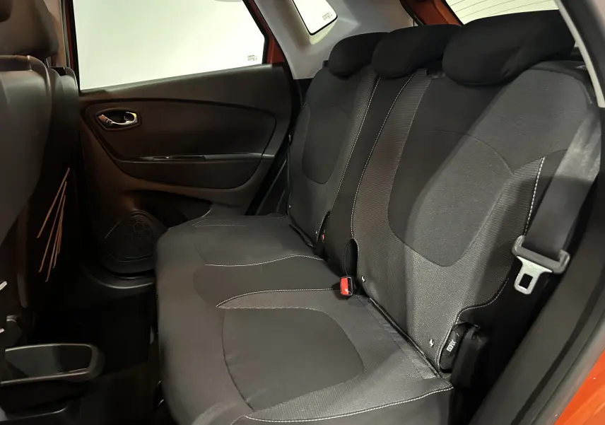 Vue intérieure sur la banquette arrière noire du Renault Captur orange, avec ceinture de sécurité et porte latérale visible.