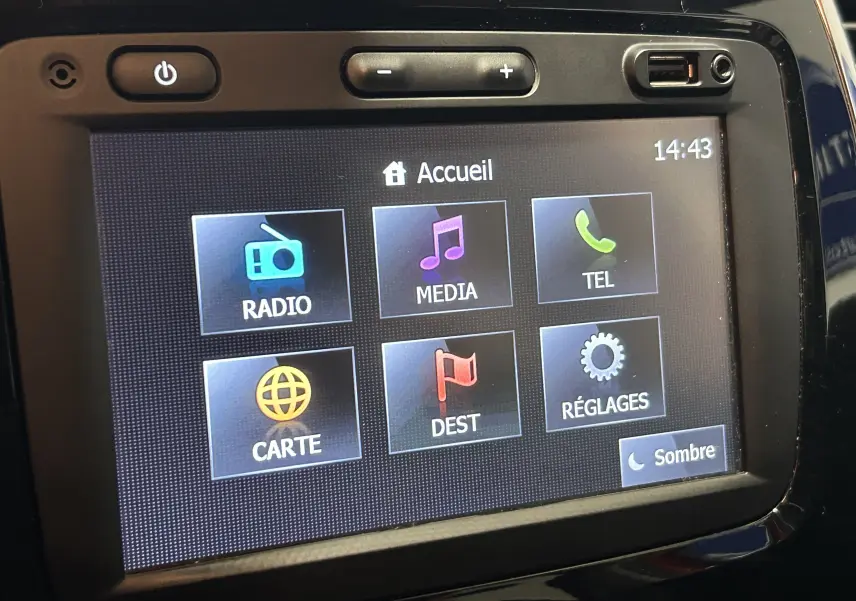 Écran tactile central du tableau de bord du Renault Captur orange, affichant le menu principal avec options radio, média et GPS.