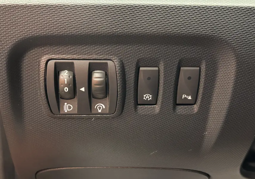 Gros plan sur les commandes de réglage des phares, tableau de bord noir du Renault Captur orange dCi 90ch Intens 2014.
