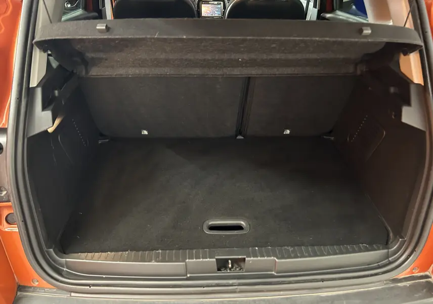 Coffre ouvert vu de l'arrière d'un Renault Captur orange 2014 avec intérieur noir et tablette de séparation relevée.