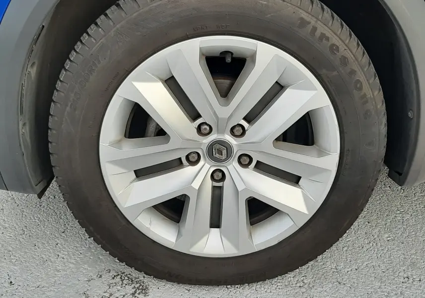 Gros plan sur la roue avant droite du Renault Captur bleu iron avec jante alliage et logo central Renault.