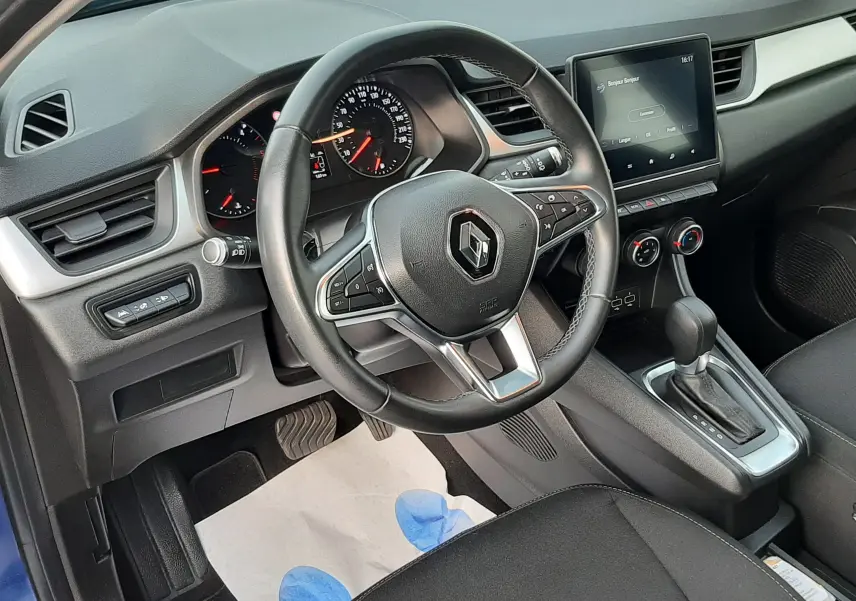Vue intérieure côté conducteur du Renault Captur bleu iron 2020, volant multifonction et écran tactile central visible.