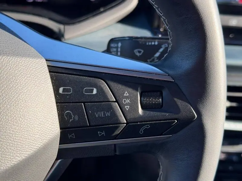 Gros plan sur les commandes à droite du volant noir du SEAT Arona 2025, avec boutons multifonctions et molette tactile.