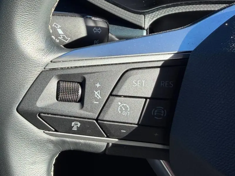 Gros plan sur les commandes noires du volant côté gauche du SEAT Arona 2025, avec molette et boutons de régulateur de vitesse.
