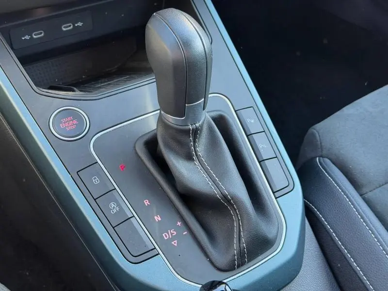 Gros plan sur la console centrale du SEAT Arona 2025, levier de vitesse automatique en cuir noir avec coutures blanches.