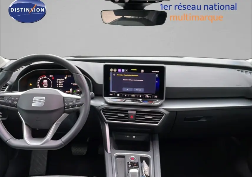 Vue intérieure du tableau de bord et volant du SEAT Leon gris Fiord, avec écran tactile central allumé.