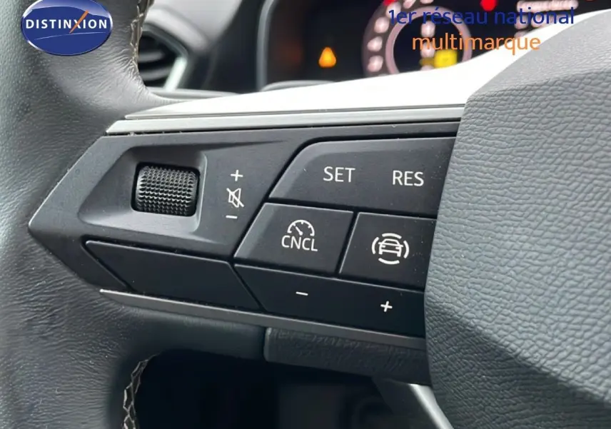 Gros plan sur les commandes au volant côté gauche d’une SEAT LEON IV gris Fiord, version 2025 essence boîte auto.