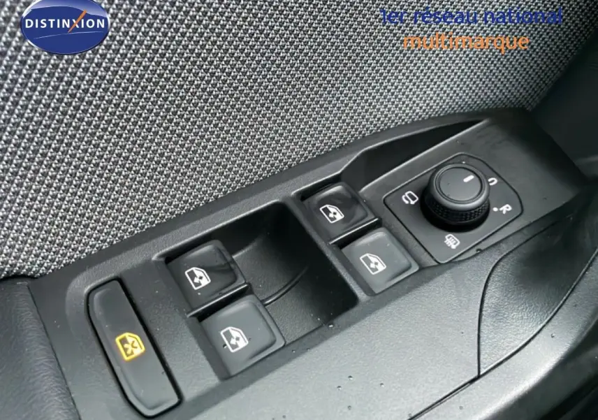 Gros plan sur les commandes des vitres électriques et rétroviseurs d’une SEAT Leon gris Fiord, côté conducteur.
