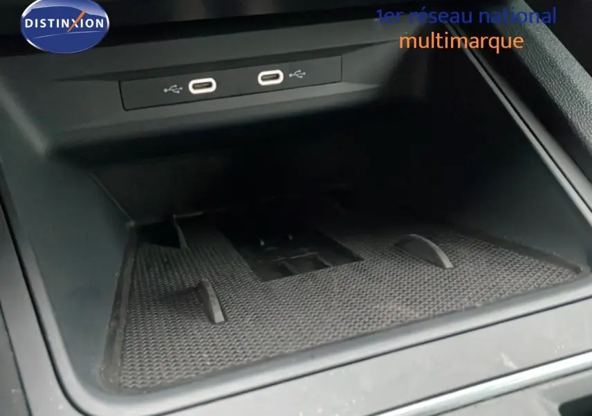 Intérieur du SEAT Leon 2025, vue rapprochée du compartiment de rangement avec ports USB, finition noire.
