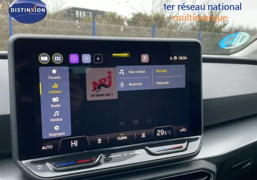 Écran tactile central du tableau de bord d'une SEAT Leon gris Fiord 2025, affichant les options multimédias et climatisation.