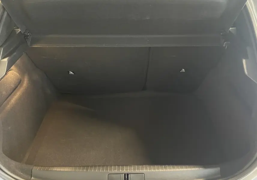 Coffre ouvert de la Peugeot 208 gris clair, vue intérieure montrant l'espace de rangement vide.