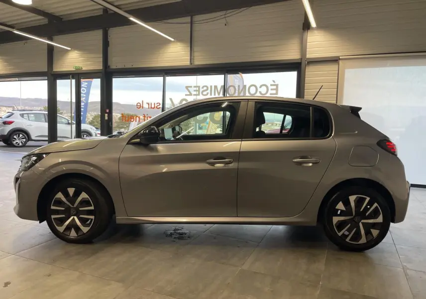 Profil droit d'une Peugeot 208 2024 gris clair avec jantes 16'' et feux arrière à LED en intérieur showroom.