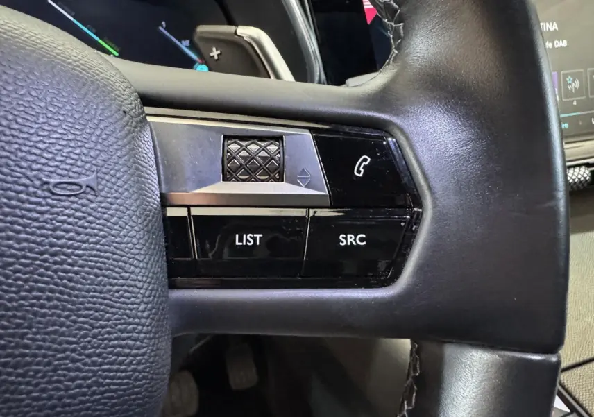 Gros plan sur le volant cuir noir du DS7 Crossback E-TENSE 225, avec commandes multifonctions et molette tactile.