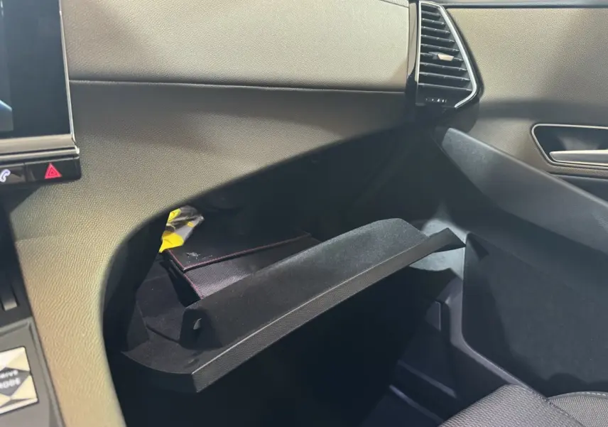 Vue intérieure côté passager du coffre à gants ouvert du DS7 Crossback gris foncé, montrant la texture du tableau de bord.