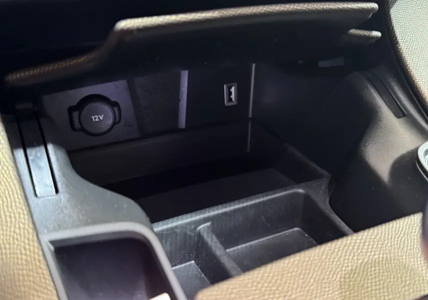 Vue rapprochée de la prise 12V et port USB dans le rangement central intérieur du DS7 Crossback gris foncé.