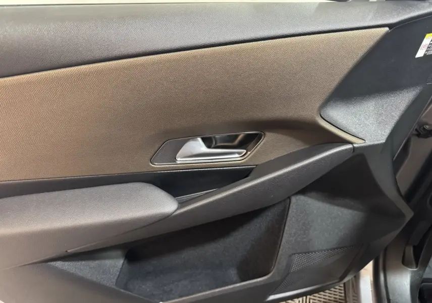 Vue rapprochée de la porte intérieure côté droit du DS7 Crossback gris foncé, avec poignée argentée et accoudoir textile.