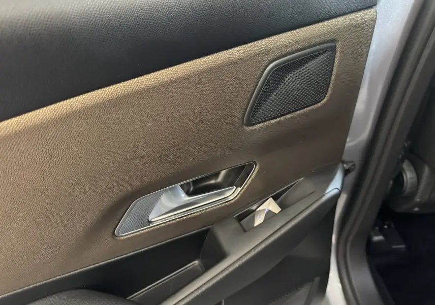 Détail de la porte intérieure côté gauche du DS7 Crossback gris foncé, avec poignée argentée et haut-parleur intégré.