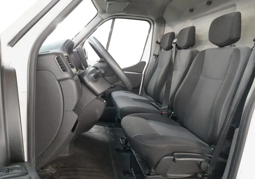 Vue intérieure côté conducteur du Renault Master L1H1 2023 blanc, montrant les trois sièges en tissu gris et le tableau de bord.
