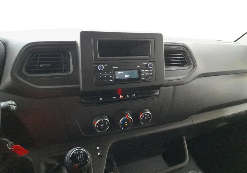 Vue intérieure du tableau de bord du Renault Master blanc 2023, avec console centrale, commandes clim et levier de vitesses manuel.