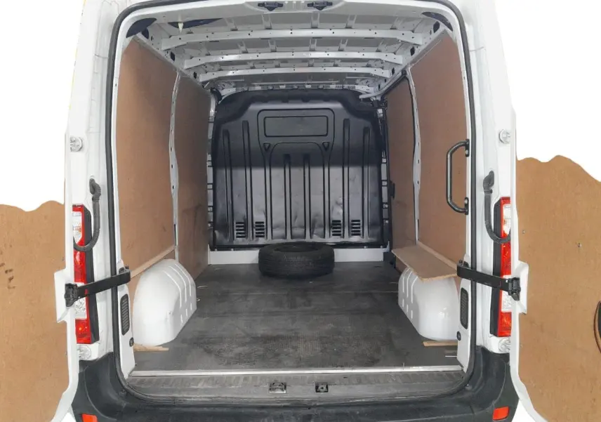 Vue arrière ouverte du Renault Master blanc 2023, montrant l'espace de chargement vide avec un pneu de secours au sol.