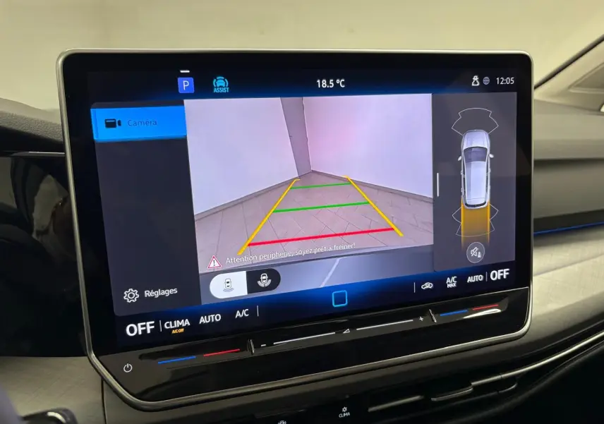 Vue intérieure sur l'écran tactile du système multimédia affichant la caméra de recul de la Volkswagen Golf 2025 reflet d'argent.