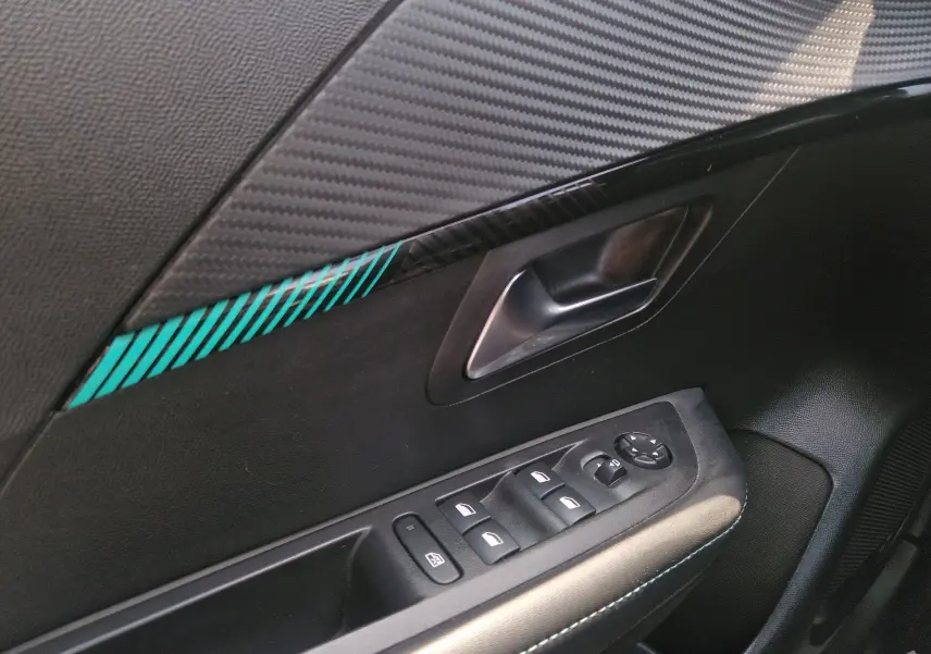Détail de la porte côté conducteur de la Peugeot 208 bleu Vertigo, avec poignée argentée et commandes électriques des vitres.