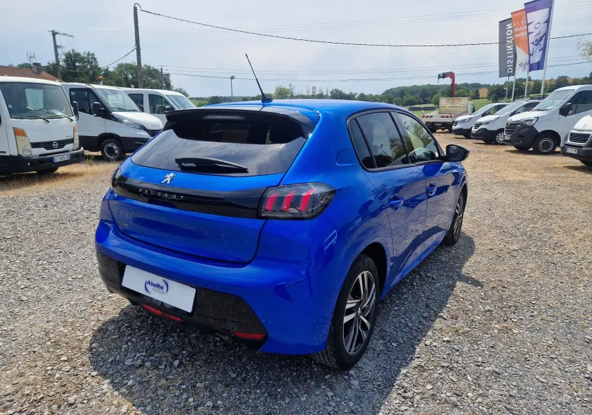 Vue 3/4 arrière droite d'une Peugeot 208 1.2 PureTech 110 Allure Pack bleu Vertigo avec feux arrière distinctifs et jantes alliage.