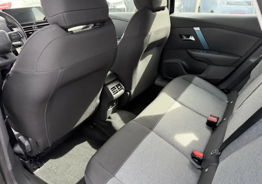Vue intérieure arrière côté droit de la banquette tissu gris et noir du Citroën C4 ë-136 2025 avec aérateurs centraux.