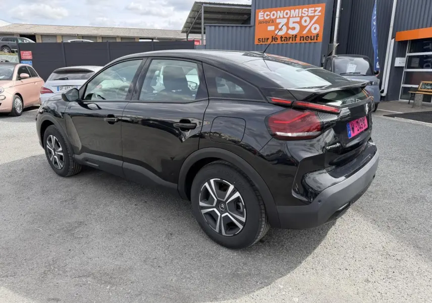 Vue 3/4 arrière droite d'une Citroën C4 électrique noire avec inserts noir brillant et jantes spécifiques.