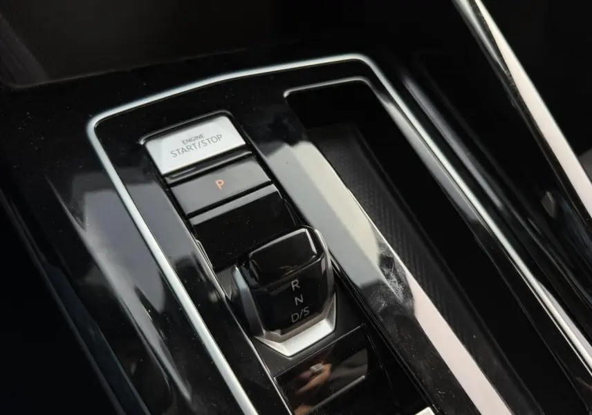 Gros plan sur la console centrale de la Volkswagen Golf VIII 2.0 TSI 190 DSG, avec levier de vitesse et bouton start/stop.