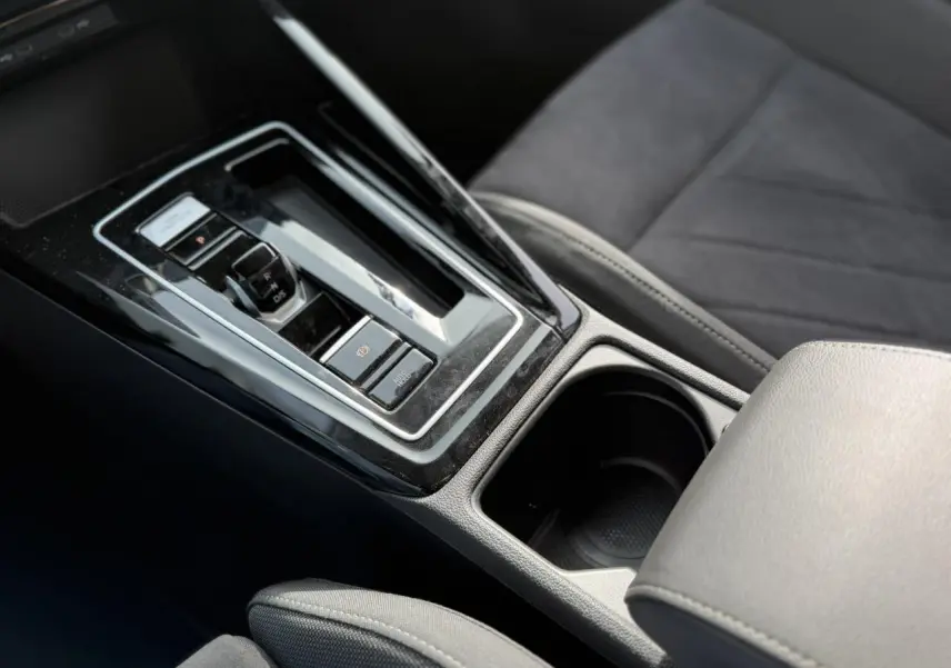 Gros plan sur la console centrale noire brillante et le levier de vitesse automatique de la Volkswagen Golf VIII 2.0 TSI 2024.