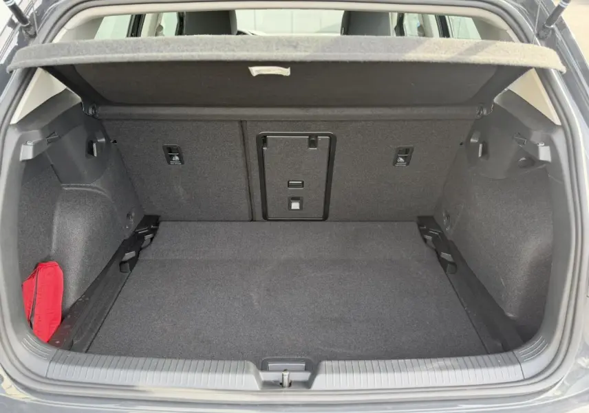Coffre ouvert d'une Volkswagen Golf VIII gris Urano, montrant un espace de chargement propre et bien agencé.