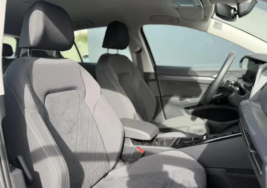 Vue intérieure côté conducteur de la Volkswagen Golf VIII Style 2024 avec sièges microfleece gris et accoudoir central.