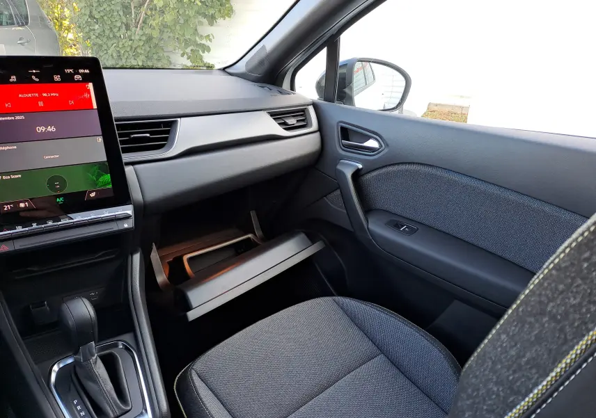 Intérieur avant droit du Renault Captur 2025 hybride, avec tableau de bord noir, écran tactile et boîte automatique visible.