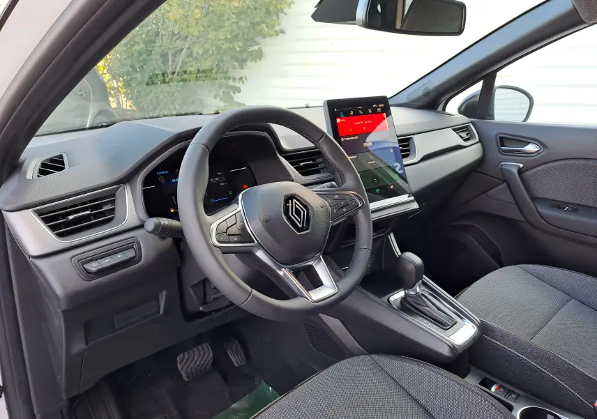 Intérieur du Renault Captur 2025, vue côté conducteur, tableau de bord gris avec écran tactile vertical et volant multifonction.