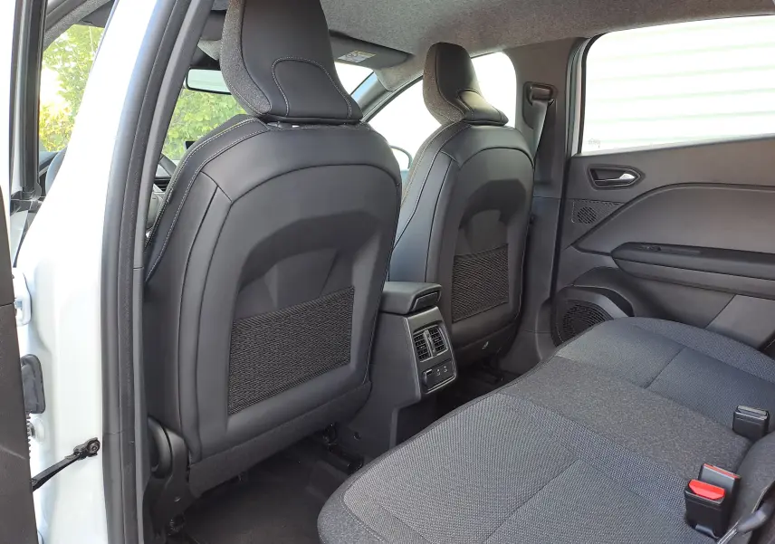 Vue arrière intérieure du Renault Captur 2025 blanc nacré, sièges avant en cuir noir et banquette tissu gris.