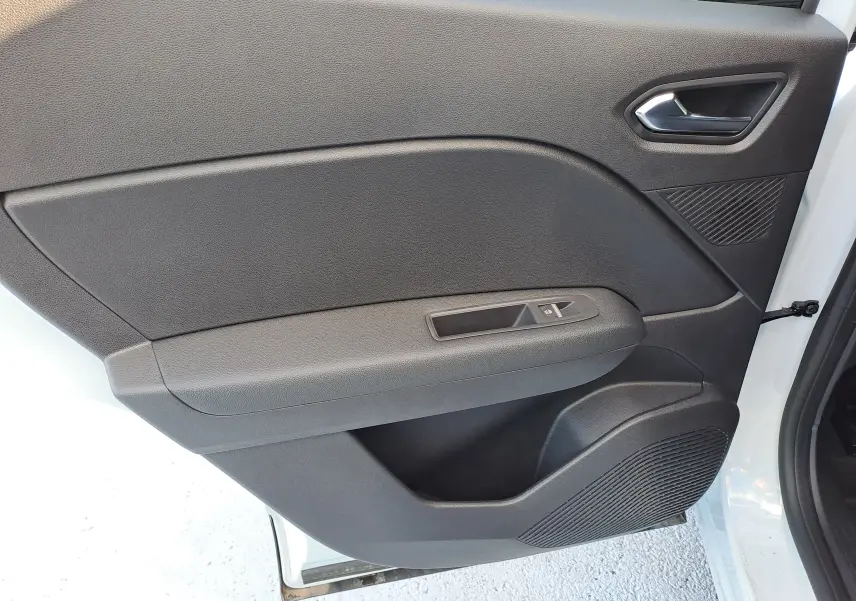 Gros plan sur la porte intérieure côté gauche du Renault Captur blanc nacré, avec commande de fenêtre et haut-parleur intégré.
