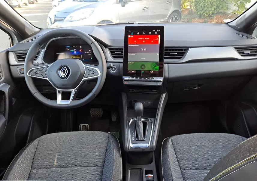 Intérieur du Renault Captur 2025 en vue frontale, montrant le volant multifonction, écran tactile vertical et console centrale avec boîte auto.