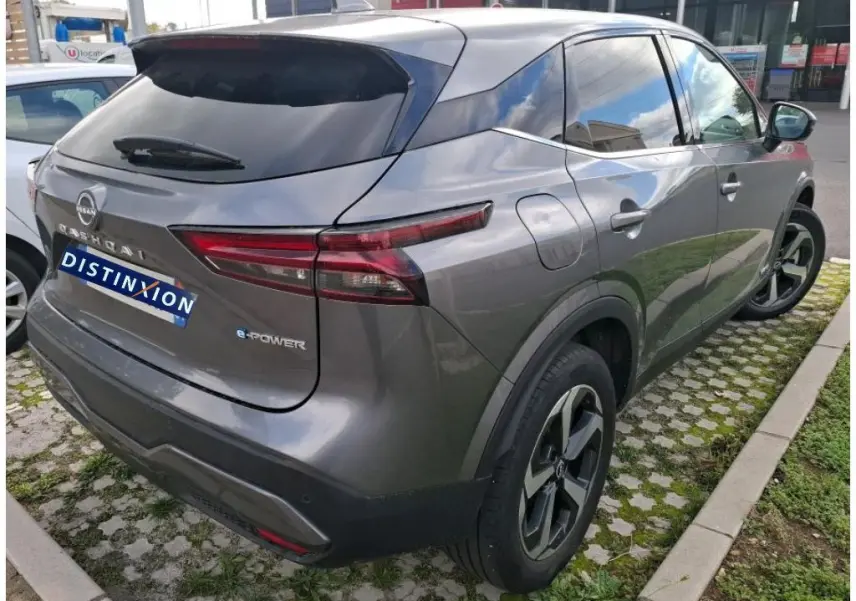 Vue 3/4 arrière droite d’un Nissan Qashqai e-POWER gris foncé 2023 avec feux arrière étirés et jantes noires.