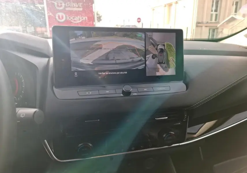 Vue intérieure du tableau de bord du Nissan Qashqai e-POWER 2023 avec écran central affichant la caméra de recul.