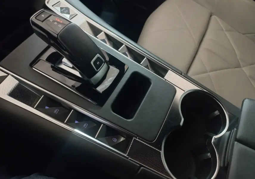 Vue rapprochée de la console centrale intérieure du DS7 Crossback gris foncé, avec levier de vitesse automatique et sièges cuir beige.