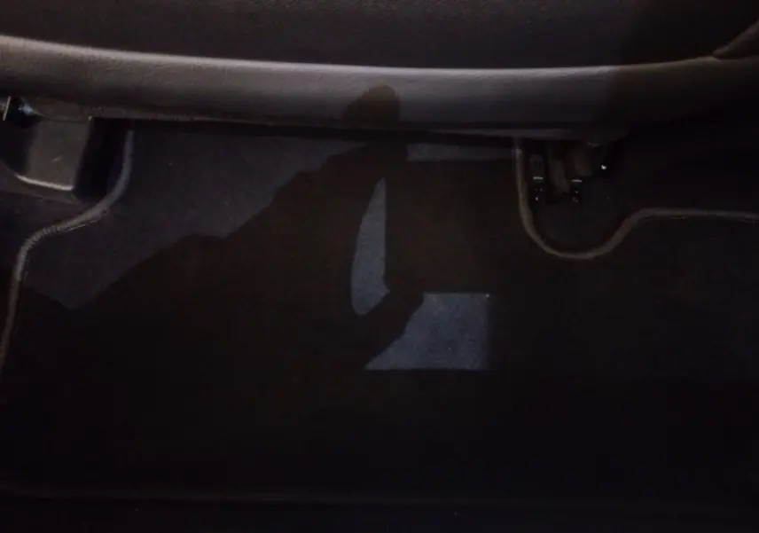 Vue du sol côté passager arrière du DS7 Crossback gris foncé, montrant la moquette et les fixations de siège.