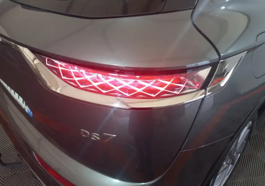 Vue arrière droite du DS7 Crossback gris foncé mettant en valeur son feu arrière à motif lumineux géométrique distinctif.