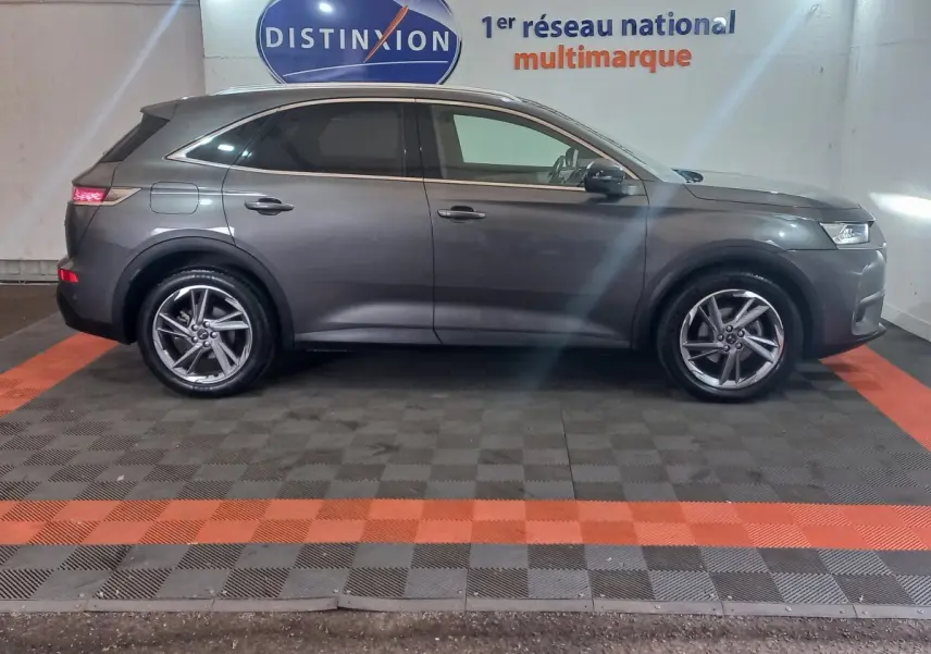 Vue latérale droite d'un DS7 Crossback gris foncé garé en intérieur avec jantes alliage et vitres teintées.