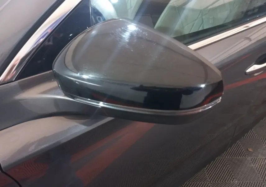 Rétroviseur côté gauche gris foncé du DS7 Crossback 2021, avec carrosserie et poignée de porte visibles en arrière-plan.