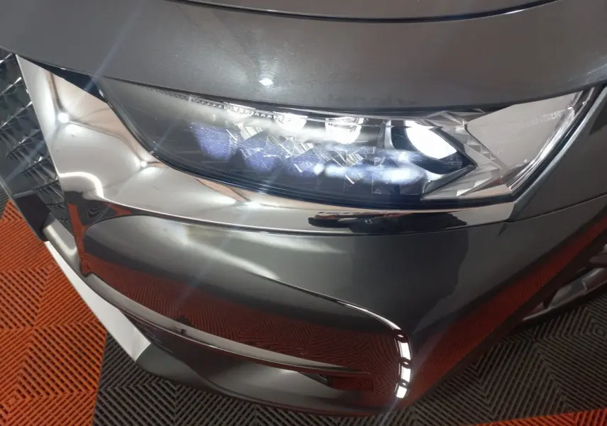 Gros plan sur le phare avant droit du DS7 Crossback gris foncé, mettant en valeur les LED et la calandre chromée.