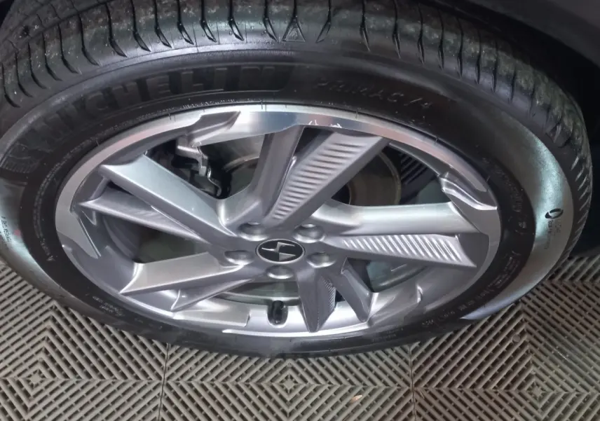 Gros plan sur la jante alliage argentée et le pneu Michelin d’un DS7 Crossback gris foncé, vue latérale.