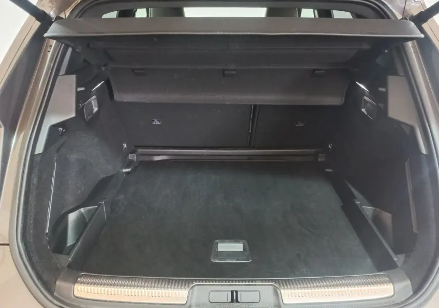 Vue arrière du coffre spacieux et propre du DS7 Crossback gris foncé, avec cache-bagages et seuil de chargement inox.
