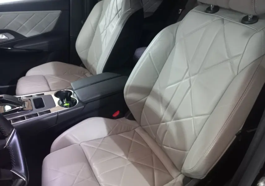 Vue rapprochée des sièges avant en cuir beige matelassé du DS7 Crossback 2021, avec console centrale et accoudoir noir.