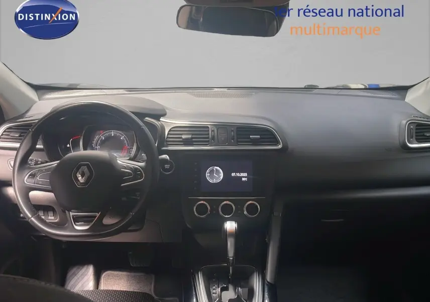 Vue intérieure frontale du tableau de bord du Renault Kadjar gris titanium, avec volant multifonction et écran central allumé.